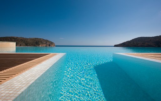 Infinity-Pool mit nahtlosem Übergang zum Meer und Panoramablick auf die Küste