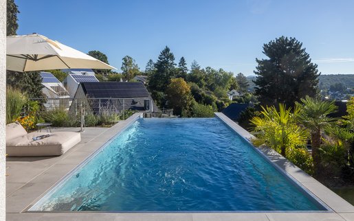 Infinity-Pool auf Dachterrasse mit Blick über die Landschaft und tropischer Bepflanzung