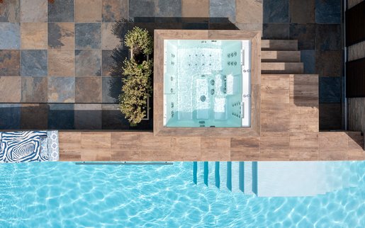 Whirlpool als Teil eines modernen Outdoor-Spabereichs mit direktem Poolzugang