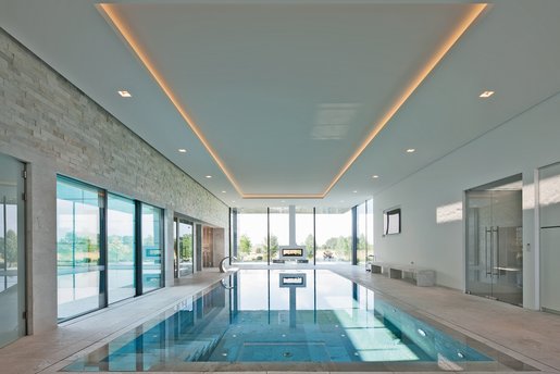 Hochmodernes Hallenbad mit klarer Linienführung, dezentem Lichtdesign und freiem Blick auf die umliegende Landschaft.